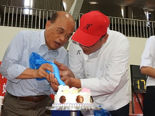 民進黨新北市長參選人蘇貞昌(左)昨到三重的新北高中體驗手作蛋糕,不忘批評新北市府花大錢蓋國民運動中心,但新北高中體育館天花板損壞卻沒立即改善。 記者祁容玉/攝影