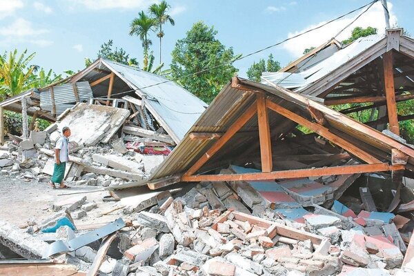 印尼龍目島廿九日發生規模六點四強震，造成許多房屋倒塌，一名男子望著已成瓦礫堆的家園發愣。 （法新社）