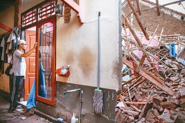 印尼龍目島遭強震襲擊，一名男子看著他幾乎全毀的家。 路透