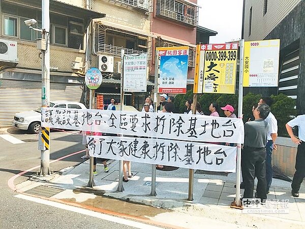 桃園市八德區和平路上一棟透天厝，10多年前在頂樓裝設了6支基地台，直至數年前屋主癌逝、妻子罹癌，一家人搬離卻留下基地台，居民6日集結在屋外抗議。（葉臻攝）