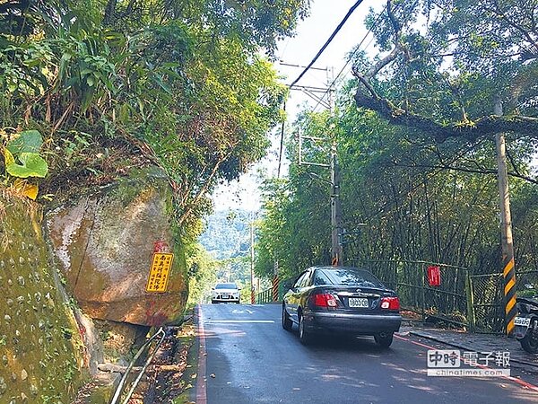 土城區承天路上有一顆巨石自山牆邊突出,部分民眾認為它是可以擋煞的「風水神石」。(許哲瑗攝)