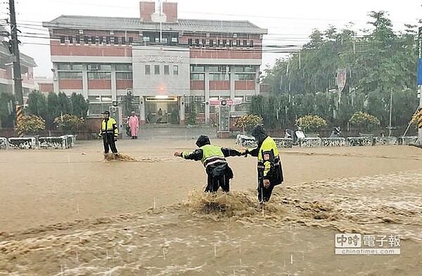 員林市14日下午又因強降雨造成淹水災情,在東山派出所前,員警冒雨指揮交通,也身陷危險中。(鐘武達翻攝)
