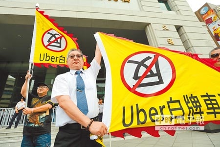 不滿政府政策矛盾、Uber威脅生計，計程車聯盟揚言上街抗議，圖為小黃運將高舉反Uber旗幟。（本報資料照片）