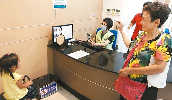 網路謠傳「無相片健保卡需強制換卡」,家長帶孩子到健保署中區業務組聯合服務中心申辦,現場提供免費拍照服務。 記者趙容萱/攝影
