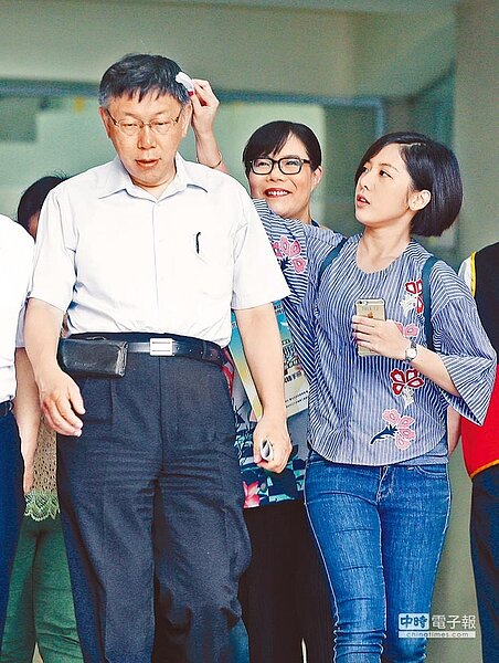 台北市長柯文哲(左)3日出席畢業生市長獎頒獎典禮,隨行人員不忘用梳子整理他的頭髮。(方濬哲攝)