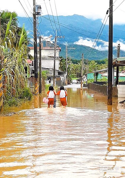 屏東內埔鄉中林村因豪大雨量造成淹水,馬路成了河流,小學生放學牽手過「河」。(林和生翻攝)
