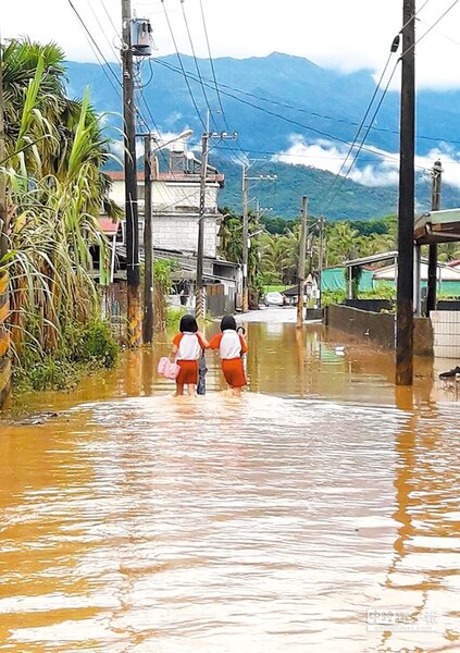 屏東內埔鄉中林村因豪大雨量造成淹水，馬路成了河流，小學生放學牽手過「河」。（林和生翻攝）