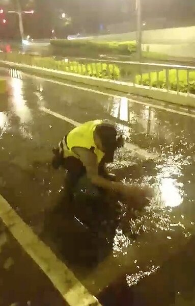 一名警員在雨中徒手清理小東地下道排水孔。圖/擷取自台南市代理市長李孟諺臉書