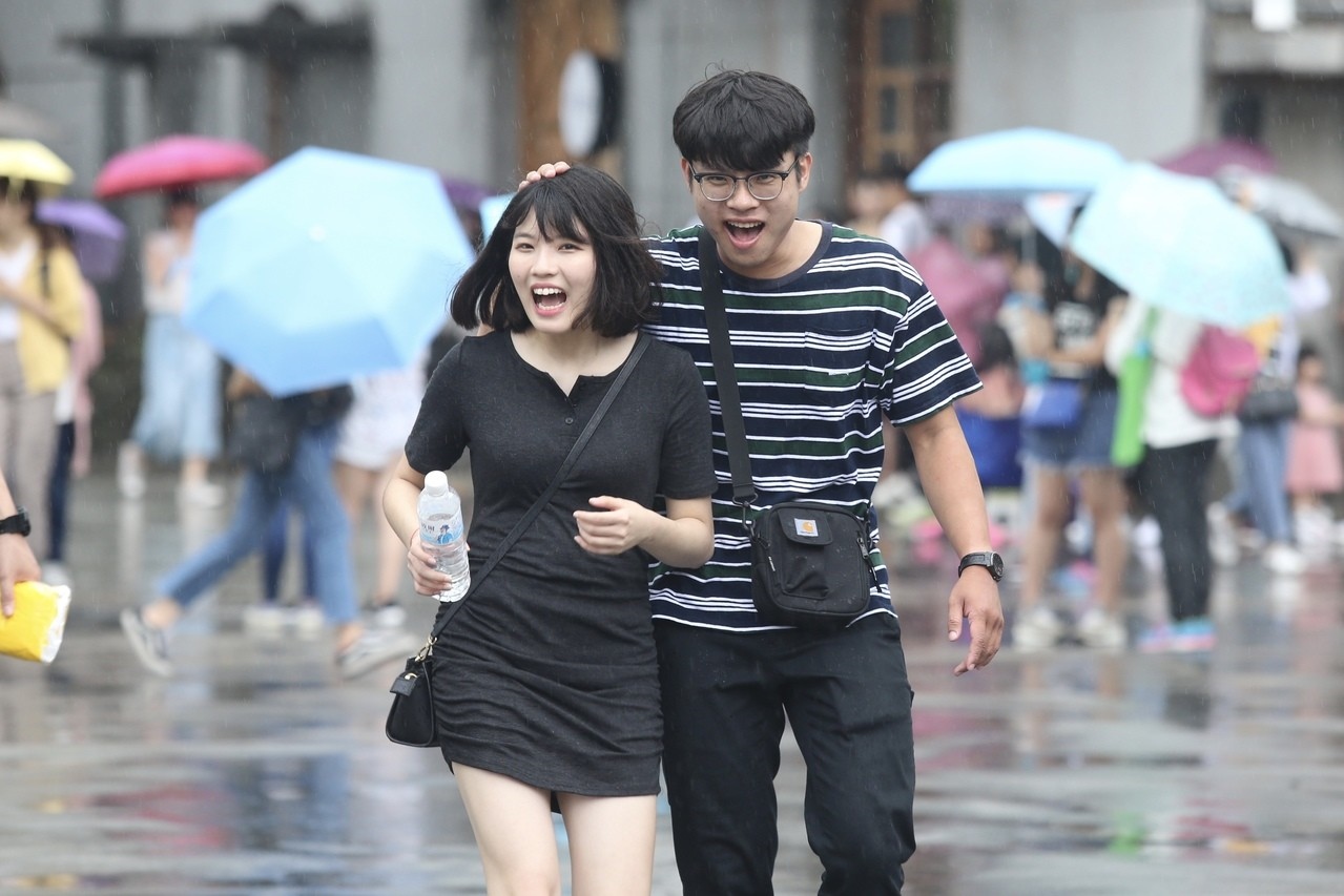 圖為台北華山文創園區附近降下大雨，街頭一名男民眾用手為女伴擋雨。 記者林伯東／攝影