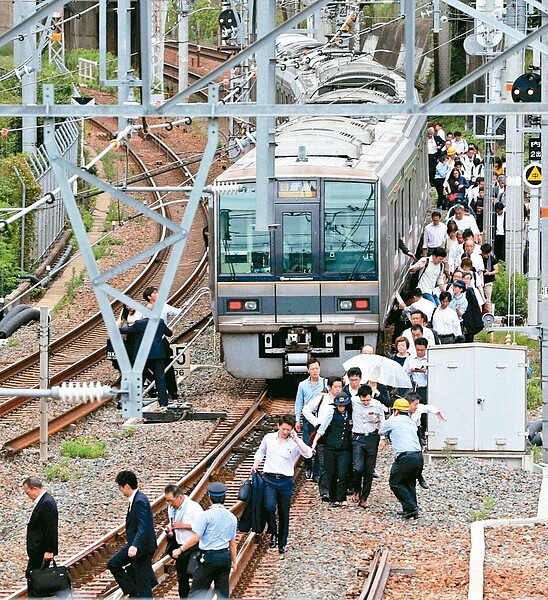 日本大阪地區十八日發生規模六點一強震，地震來襲時一列電車立即停駛，乘客在工作人員引導下疏散。 歐新社