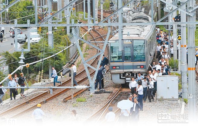 日本大阪發生強震，電車停駛，因須進行安全檢查，旅客被迫下車，沿鐵軌走回車站。（法新社）