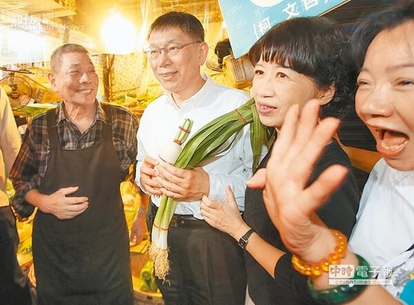 台北市長候選人柯文哲（左二）與夫人陳佩琪（右二）13日到東門市場拜票，攤商送上菜頭及蒜祝福好彩頭。（王英豪攝）