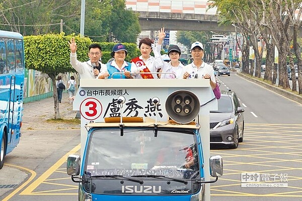 國民黨台中市長候選人盧秀燕（中）站上戰車掃街拜票，主播妹妹盧秀芳（右二）比出OK手勢，助選架式嫻熟。（王文吉攝）