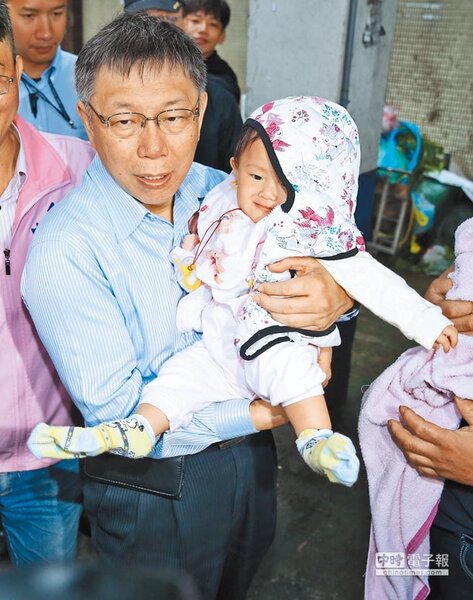 台北市長候選人柯文哲（左）17日前往環南市場拜票，並抱起商家的小嬰兒合影，相對於柯文哲僵硬的表情，小嬰兒的神情更加搶戲。（姚志平攝）
