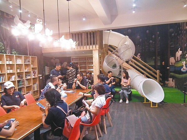 重新翻修的圖書館有咖啡吧檯,書牆及動力發電腳踏車,還有挑高平台及溜滑梯,牆面還繪成北極熊走進森林的圖示。 記者尤聰光/攝影