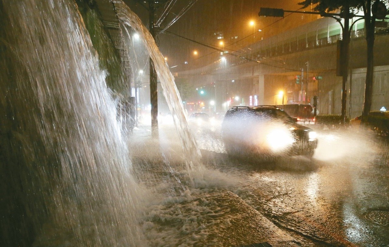 基隆基金一路昨晚因地勢加上豪雨，出現不少猶如小瀑布的路段，來往的人車得在水流中逆勢而上。 記者許正宏／攝影