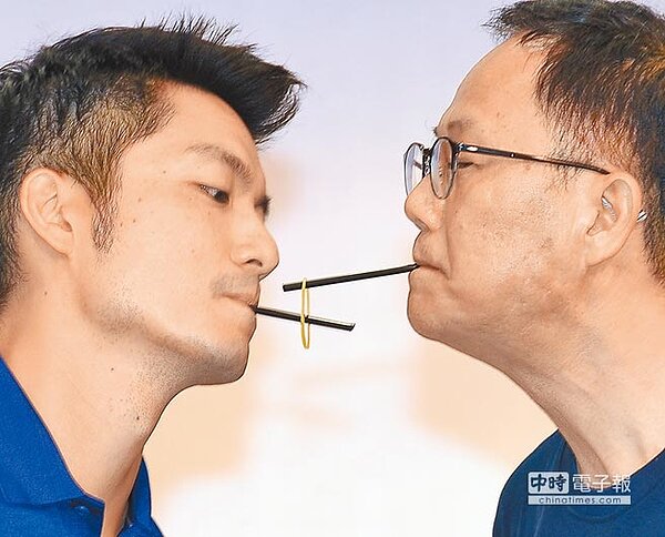 國民黨台北市長參選人丁守中（右）8日出席青年後援會成立大會，並且與立委蔣萬安（左）一起玩起口啣黑色吸管傳接橡皮筋的競賽。（季志翔攝）


