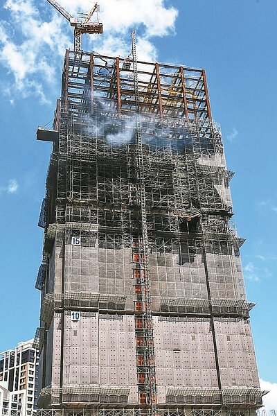 新北市新莊區一處24層樓工地燒了17小時,上午仍可見高樓層冒出白煙。 記者王騰毅/攝影