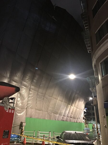 中颱山竹颱風雖已遠離,但強風陣雨仍持繼發威,新北市永和區一處都更工地鷹架,疑似不堪強陣風傾倒,倚靠在隔壁大樓的外牆上,警方現場拉警戒線封鎖進行交管。圖/警方提供