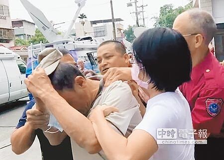 把直升機當小黃的葉姓登山客，19日在妻子陪同下到南投縣消防局道歉，義消試圖脫下他的帽子，結果發生拉扯。 （廖志晃攝） 