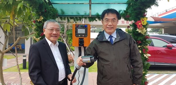 中油在台南建置全台第一座智慧綠能加油站，台南市長黃偉哲（右）今天在中油董事長戴謙陪同下參觀，手持機車充電槍。 記者修瑞瑩／攝影
