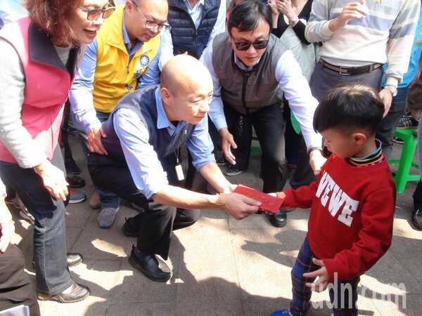 高雄市長韓國瑜發紅包，看到小孩，都會蹲下來發給小朋友。記者謝梅芬／攝影 