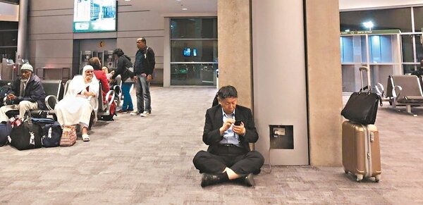 台北市長柯文哲臉書照片，他身穿西裝在國外機場席地而坐，以公用電替手機充電，引發熱議。 圖／取自柯文哲臉書