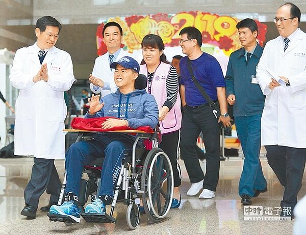 秦良丰(前排左二)去年在漢光演習預演發生跳傘意外,經過三軍總醫院、童綜合醫院的救治,5日從三總本院離開時揮手面露笑容,準備搭乘高鐵轉回高雄總醫院復健治療。(張鎧乙攝)