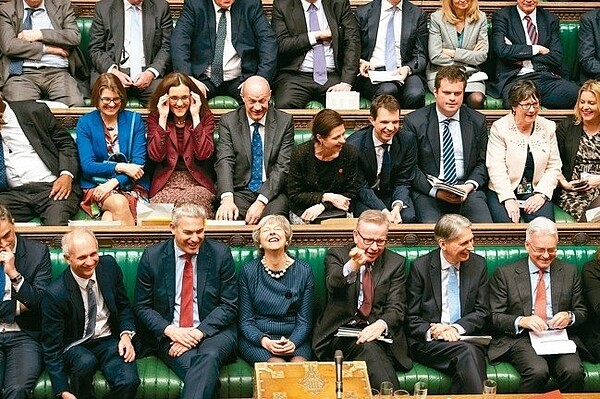 英國國會14日以壓倒性票數通過脫歐至少延後三個月到6月30日,首相梅伊(前排右四)出現近日難得的笑容。 路透