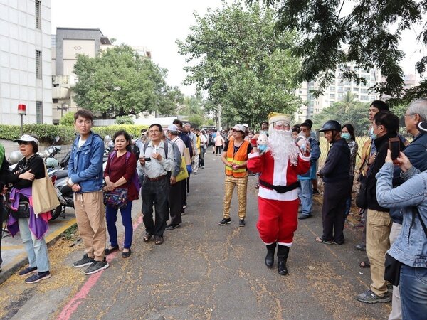 國民黨高雄市黨部前排隊隊伍目測超過300公尺，有人配合聖誕節，打扮成聖誕老人販賣韓周邊商品。記者張媛榆／攝影
