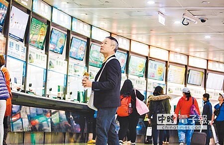 國道客運票價蠢蠢欲動,經交通部協商春節前凍漲;圖為民眾邊觀看客運總站各家資訊面板邊來回走動。(郭吉銓攝)