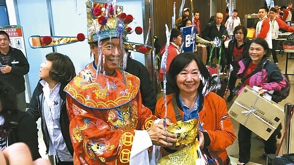 臺灣港群國際旅客第120萬人次幸運兒朱孟榮,在獲得財神爺送上金元寶時,驚喜不已。 記者吳淑君/攝影