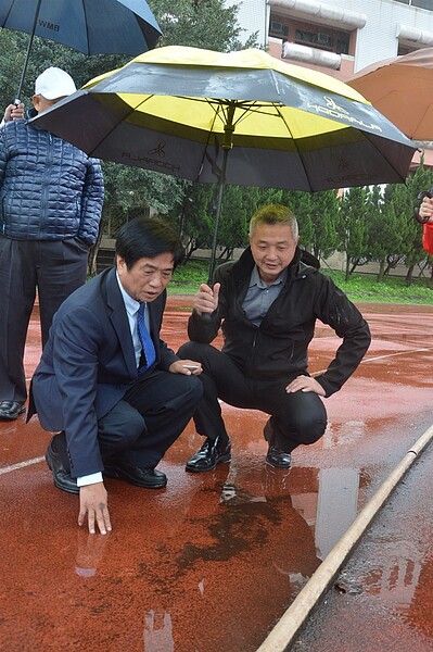 吳琪銘（左）雨中邀教育部、教育局官員勘查高中操場跑道，右為校長陳棟遠。記者施鴻基／攝影 