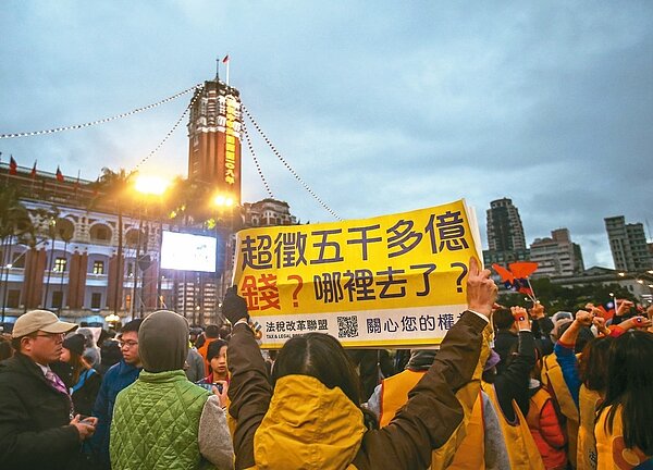 廿多名法稅改革聯盟成員，昨天在總統府前元旦升旗活動現場高舉標語，要求財政部還稅於民。 記者陳柏亨／攝影