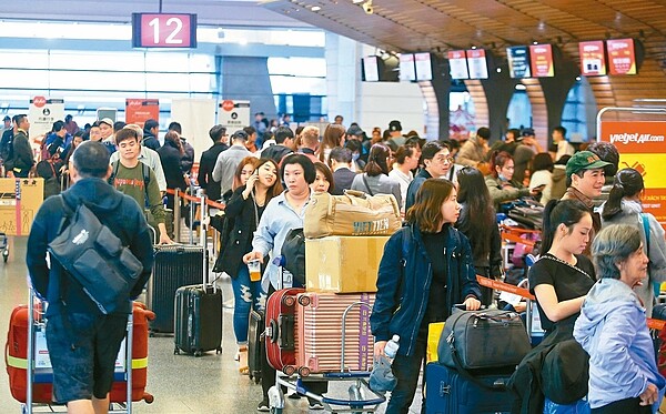 桃園機場今年春節恐大塞機,預估每天平均起降航班八百架次,遠超去年的七百架次,平均每天每班延誤時間最多恐達到四小時。圖為桃園機場旅客在報到櫃台等候的情形。 記者鄭超文/攝影