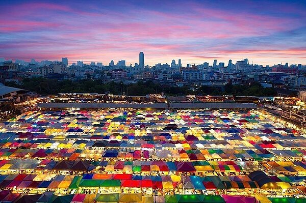 泰國首都曼谷的拉差達火車夜市入夜前景色。拉差達火車夜市交通方便,向來是自由行與背包客必定造訪的景點之一。許多旅客會到相鄰百貨公司4樓停車場,拍攝五彩繽紛的美景。(畫面翻攝/Facebook/Hug Thailand)