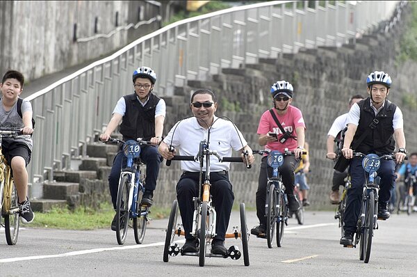 侯友宜與身心障礙者一起駕駛手搖車到大漢橋,再換騎乘自行車一路到華江橋,並欣賞沿途融合新北特色的世界名作「新北上河圖」,另外侯友宜也與「拾穗」、「熱氣球」兩幅立體堤防彩繪拍照。圖/新北市高管處提供