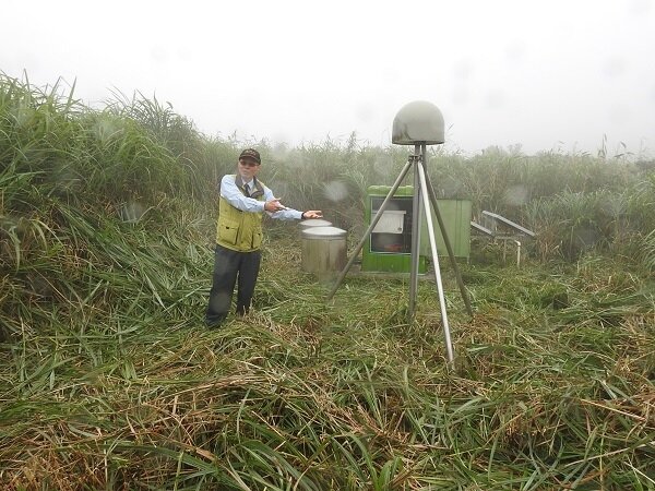 林正洪研究員與小油坑的地球物理監測儀器，由左至右為井下傾斜儀、地震儀及GPS接收器（圓頂），全方面監控火山活動。（圖／科技部提供）