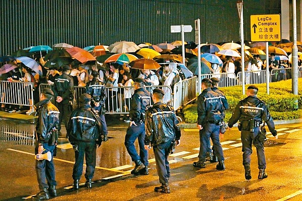 引發百萬港人上街抗議的「逃犯條例」修正草案,今將進行二讀辯論,香港民陣等團體發起包圍立法會和罷課、罷工、罷市,施壓港府撤回修例。昨晚立法會大樓前已有群眾聚集,現場警力持續增加戒備。 特派記者王騰毅/攝影