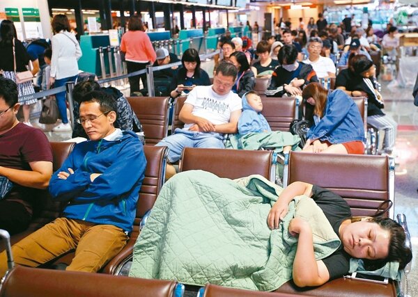 長榮空服員罷工今進入第四天，由於辦理簽轉業務須領號碼牌，昨天許多旅客到現場等待 ，累到睡在長椅上。 記者鄭超文／攝影