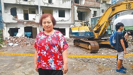 新莊區光明段危老屋24日上午拆除,原屋主楊媽媽站在工地前合影。(吳亮賢攝)