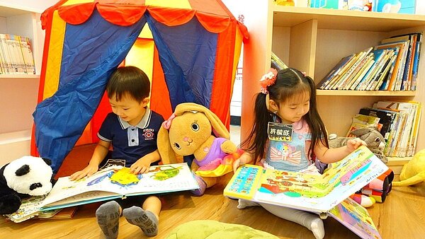 新北市立圖書館推出「布偶夜宿圖書館」活動，4歲小女孩許毓庭（右）也帶著心愛的兔子玩偶來圖書館讀書，晚上將要把玩偶留宿。圖／新北市立圖書館提供