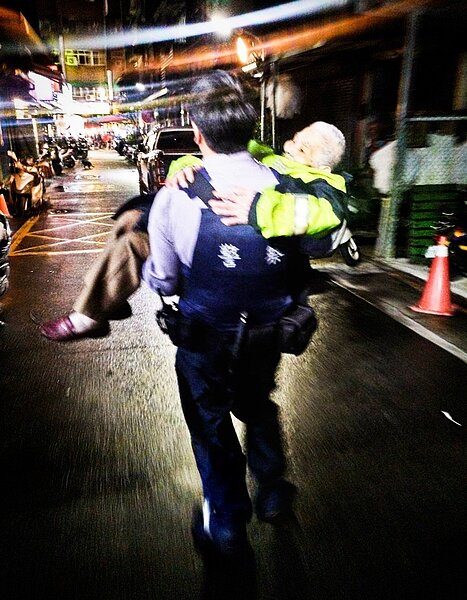 27歲的徐員擔服巡邏勤務,看見張婦獨自在雨中徘徊,立即上前關心,徐員見張婦全身不停發抖,已無力行走,便脫下警用雨衣覆蓋在張婦身上,並將她抱起,送至騎樓躲雨。記者李隆揆/翻攝