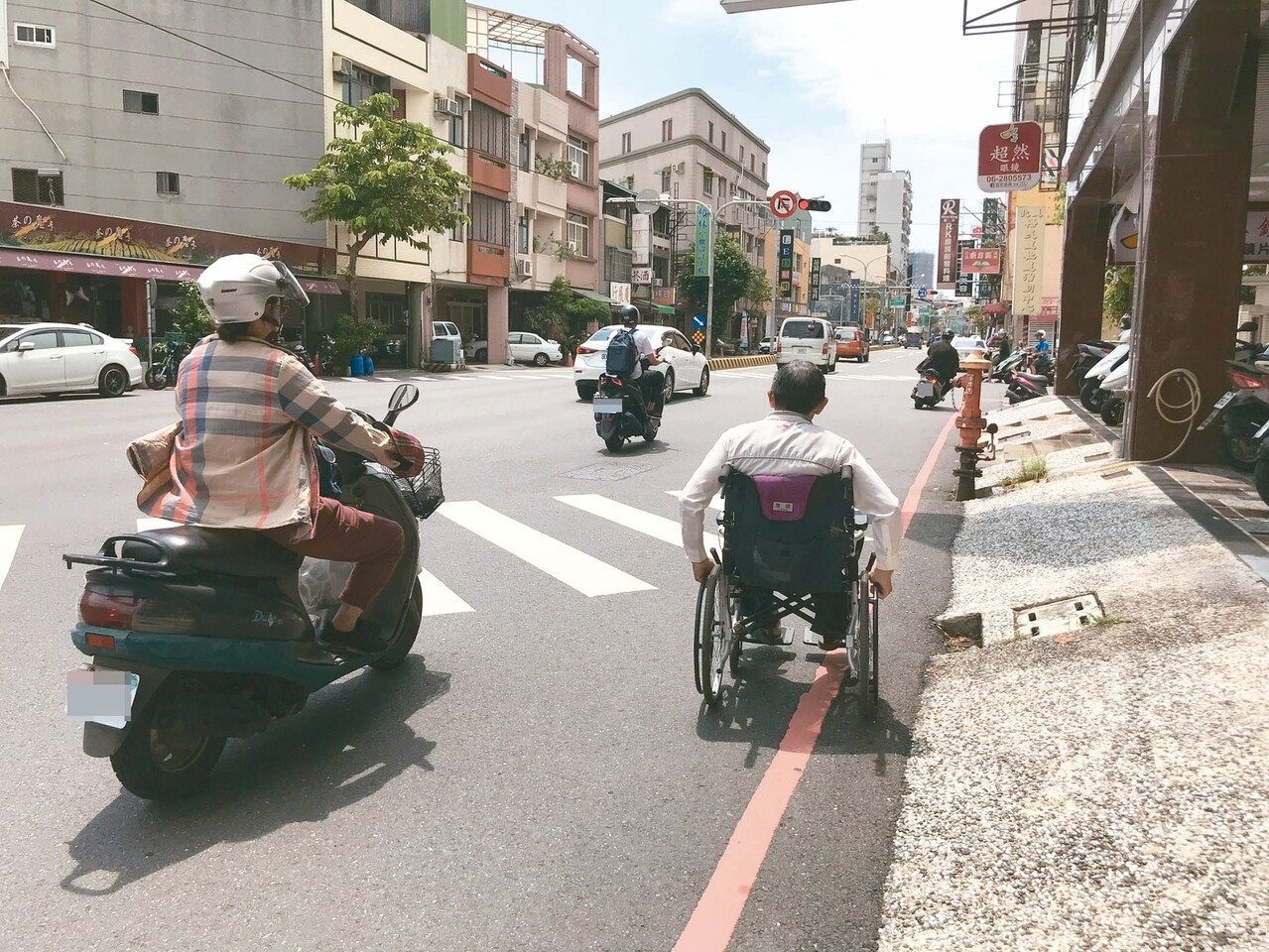 騎樓不暢通，許多身障者必須乘輪椅與車爭道，增添危險。 記者鄭維真／攝影