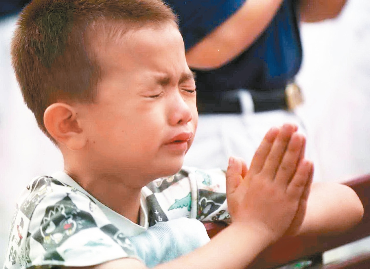 當年目睹震災的慘狀，小男孩哭紅眼，雙手合十為去世親人祝禱。圖／聯合報系資料照片