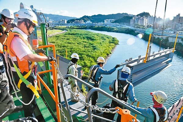 新北市長侯友宜(左前)日前到安坑輕軌擔任「一日工頭」,了解安心橋橋體鋼桁架吊裝作業內容。 圖/新北市捷運局提供