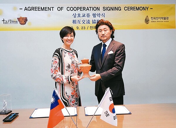 十三行博物館館長陳春蘭(左)贈送鎮館之寶「人面陶罐」複製品給韓國全谷史前博物館,象徵雙方合作結盟的開始。 圖/新北市政府提供