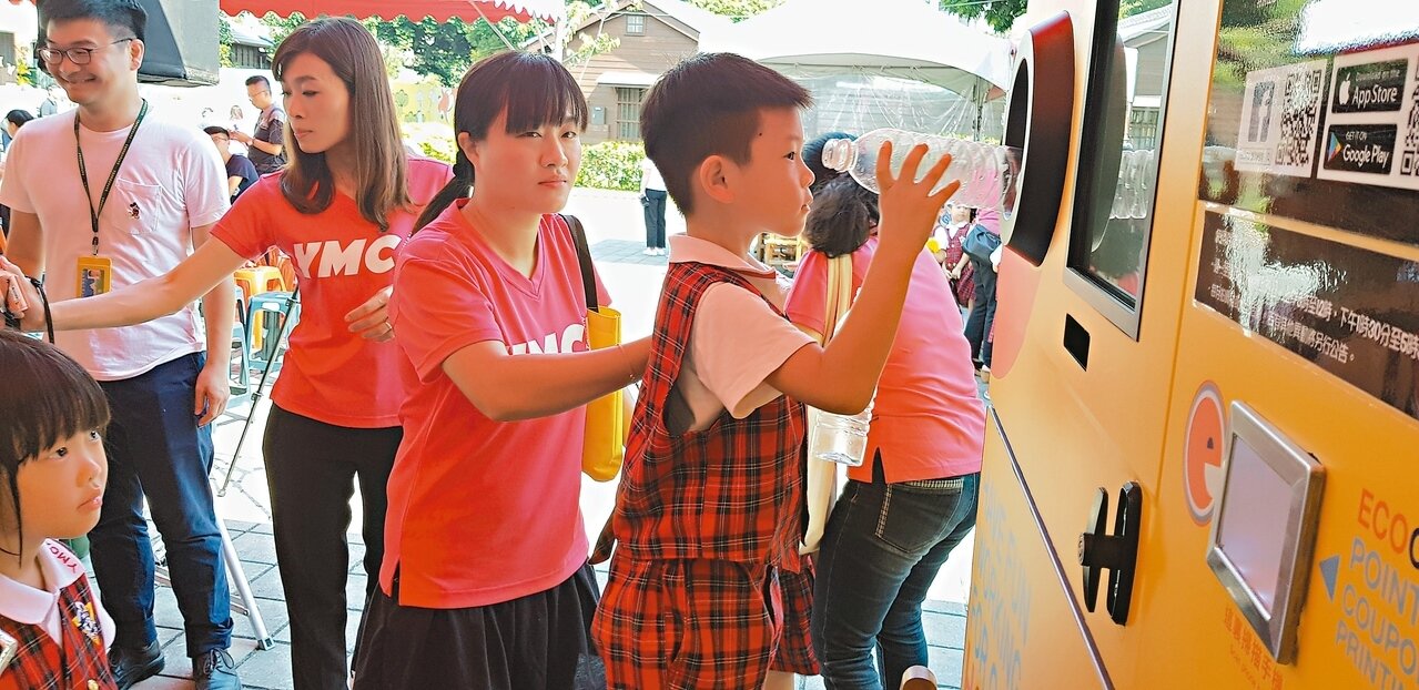 台南市幼兒園的小朋友把寶特瓶丟進回收機裡。 圖/記者修瑞瑩攝影