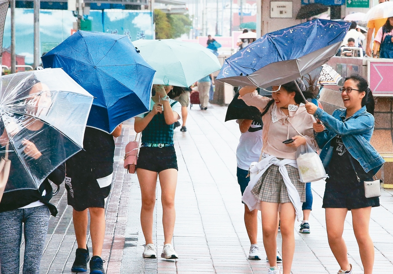 氣象局昨晚發布米塔颱風陸警，台北間歇性風雨已讓路人雨傘開花。 記者潘俊宏／攝影