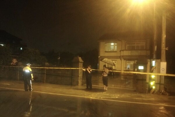 桃園市平鎮區今天傍晚降豪大雨,金陵路部分路段淹水,平鎮警分局分局長黃炳訓,親自冒雨涉水拉設封鎖線管制車輛通行。圖/平鎮警分局提供